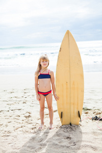 年轻的女孩，站在海滩上的冲浪板