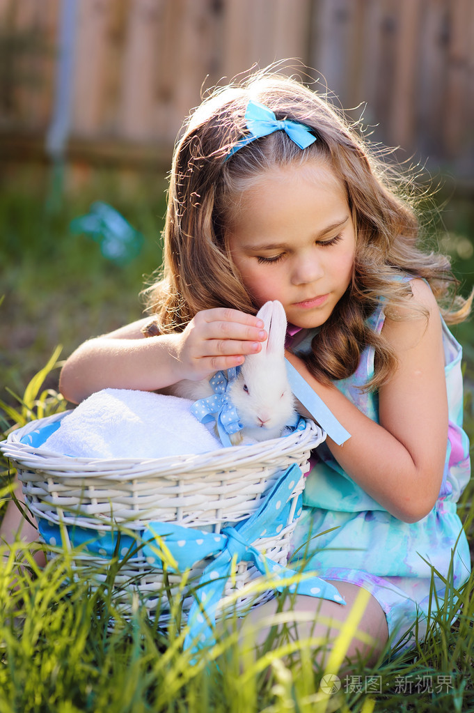 可爱的小女孩与小兔子有一个复活节在绿草