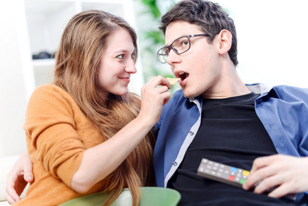 年轻漂亮的女人，给她亲爱的前面，电视的食物