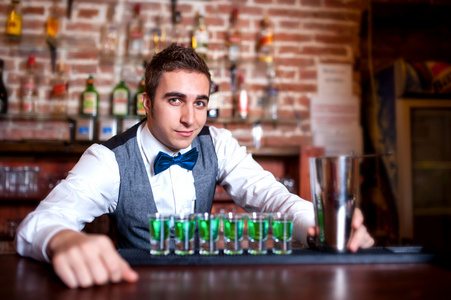 年轻男酒保酒精镜头和鸡尾酒酒吧后面的肖像