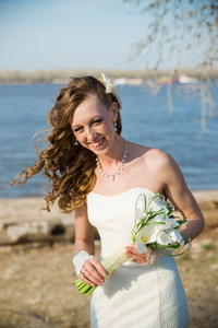美丽的新娘穿着白色连衣裙海岸的河