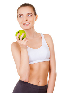 运动服装拿着一个绿色的苹果和微笑的女人