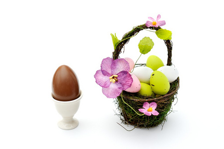 多彩漆的复活节彩蛋在篮子和蛋杯巧克力蛋