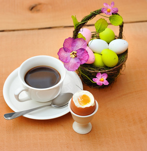 涂的复活节彩蛋在篮子里，一杯黑咖啡和蛋杯