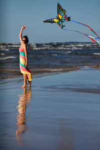 在海滩上玩风筝的年轻女子