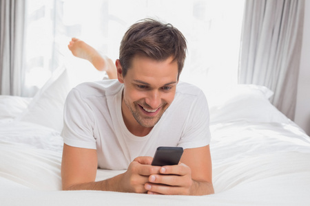 年轻男子发短信在家里的床上