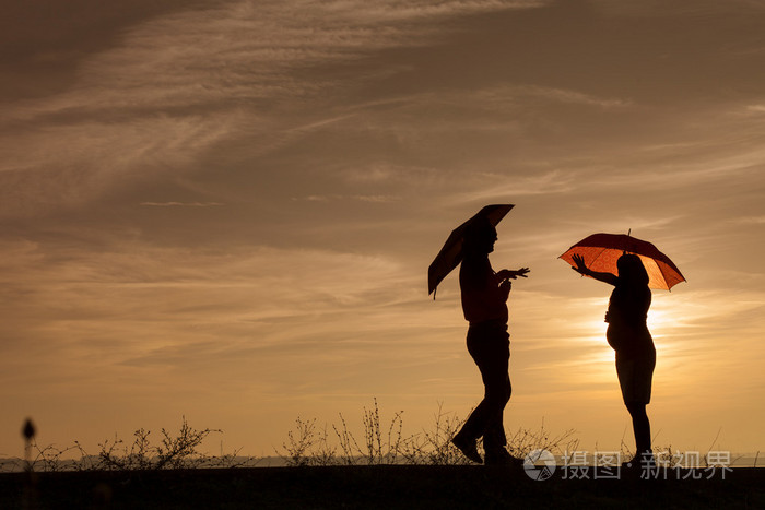 怀孕的女人和一个男人在夕阳中的剪影