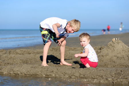 男孩和妹妹在一起在沙滩上玩