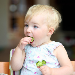 女孩咬着美味的新鲜熟花椰菜