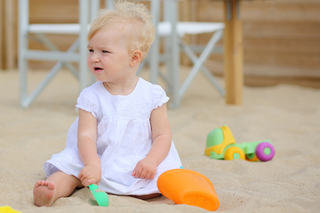 宝贝女孩玩玩具在海滩咖啡馆在沙子里