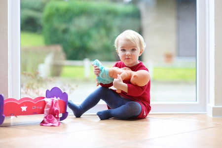 女孩玩玩具娃娃坐在地板上的瓷砖