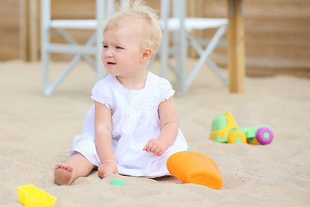 宝贝女孩玩玩具在海滩上的沙子