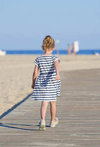 在海滩度假的小女孩。从背面