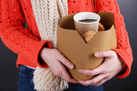 女人抱着咖啡和饼干在黑色背景上的框