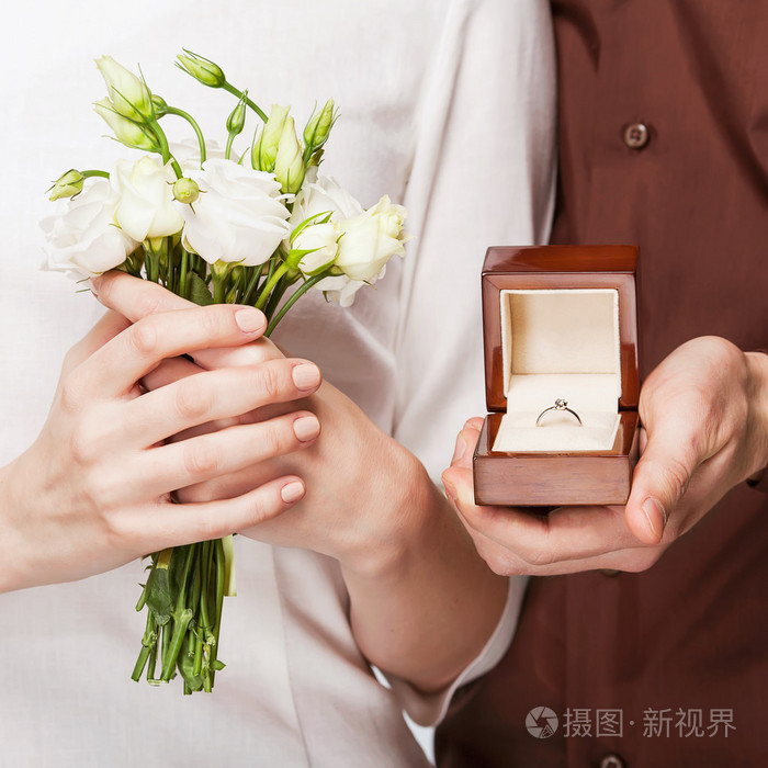 新婚夫妇拿着戒指盒和一束鲜花