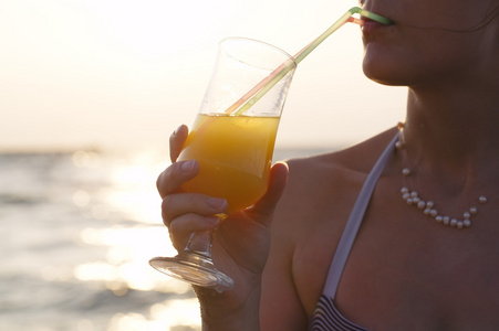 女人在日落时喝一杯清爽的鸡尾酒