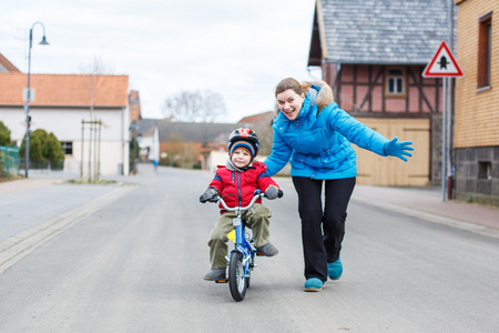 年轻的妈妈教她 3 年岁的小儿子骑自行车