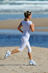 在夏天在海滩上慢跑的年轻女子图片