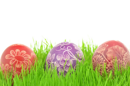 三抓手工制作的复活节彩蛋在白色背景上孤立的草地