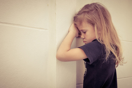悲伤的小女孩站在了一天时间在壁面附近的肖像