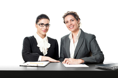 两个微笑着坐在前台的女企业家