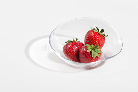 新鲜的草莓水果放在一个白色背景的玻璃盘子里。