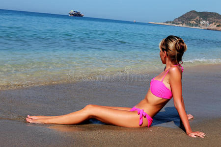坐在海滩上的年轻女子的侧视图