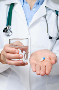 医生拿着一杯水和一颗药丸