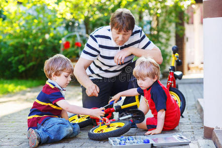 父亲和两个小儿子一起修理自行车