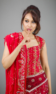 一位年轻的印度妇女，手指放在嘴唇上站着