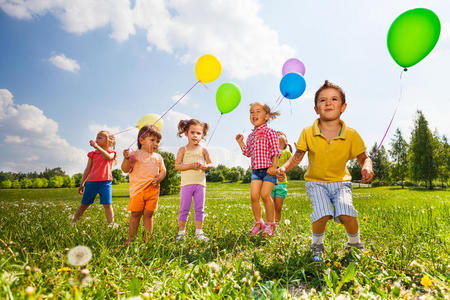 孩子们拿着五颜六色的气球在田野里奔跑