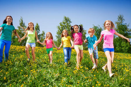 快乐的孩子们在绿色的田野里奔跑和牵手