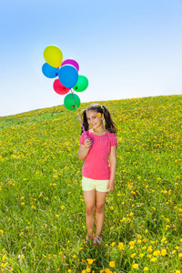 可爱的女孩拿着气球站在草地上