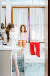 可爱的小女孩坐在浴室的窗户上