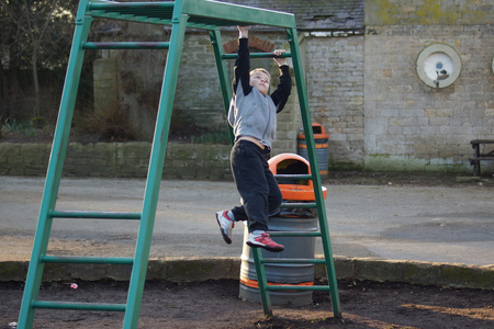 单杠上攀爬的年轻男孩照片