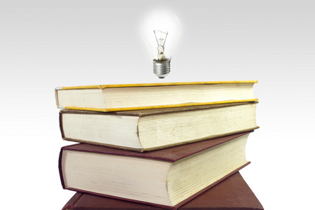 一摞书用灯泡。智慧和知识的概念