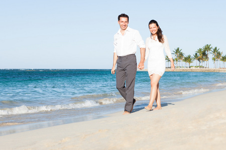 幸福的夫妇手牵着手走在沙滩上时