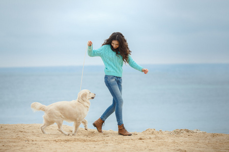 美丽的年轻女子在海边上玩狗的肖像
