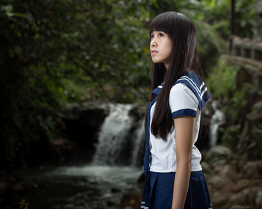 亚洲女学生站在瀑布前