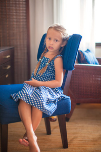 小可爱的女孩，在旅馆房间里的椅子上的肖像