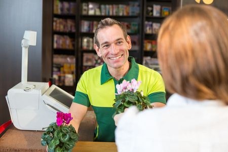 收银员或店主在花卉商店或零售商店服务客户端