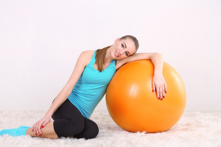 用橙色的球，在健身房锻炼的年轻美丽健身女孩
