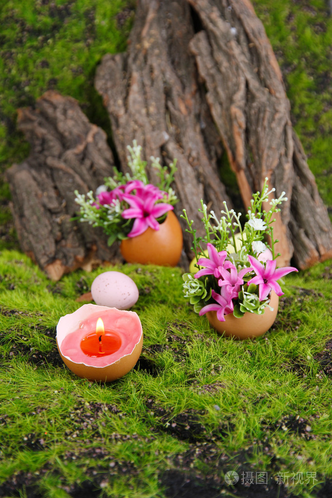 概念的复活节组成.燃烧的蜡烛在鸡蛋和上绿色的花朵草背景,特写