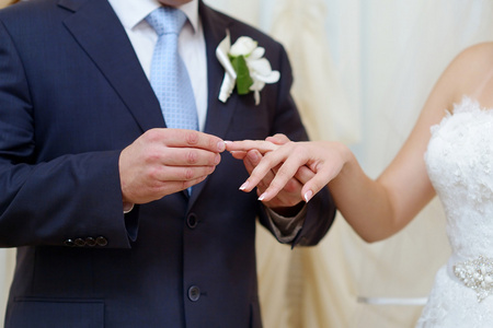 新郎把戒指往新娘的手指上
