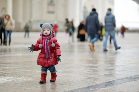 蹒跚学步的女孩在一个城市在冬日乐趣