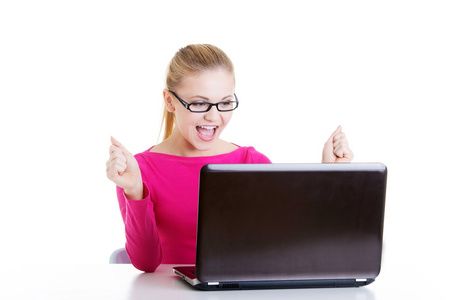 年轻快乐的女人坐在笔记本电脑前