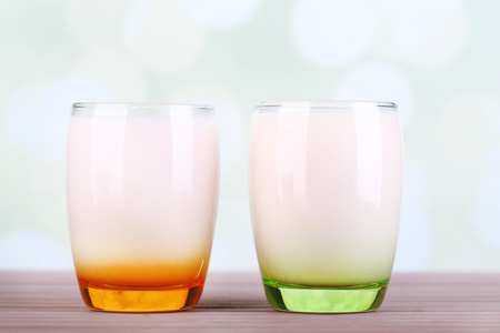 美味的酸奶，水果口味在彩色木桌前，在明亮的背景上一付眼镜