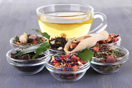 杯茶，芳香干茶叶在碗上木制背景