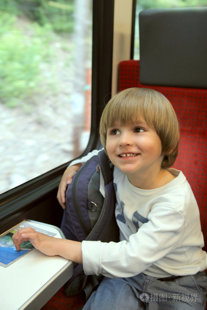 小男孩坐在火车的窗口旁边