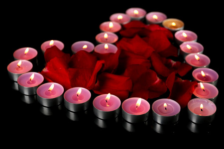 美丽的玫瑰花瓣，手持蜡烛，在深色背景上